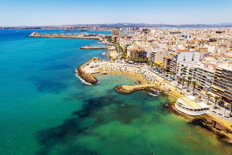 Luchtfoto van de kustlijn van Torrevieja, met haar turquoise baaien en haven op de achtergrond